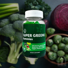 Bottle of Super Greens Gummies surrounded by fresh vegetables on a dark background