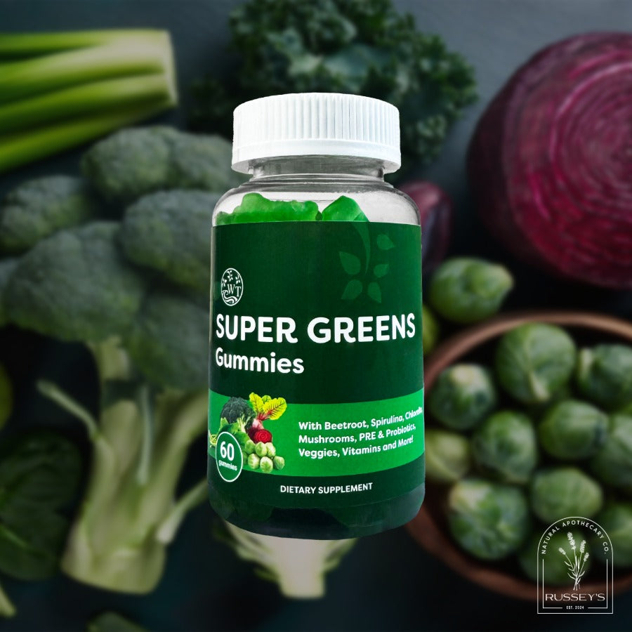 Bottle of Super Greens Gummies surrounded by fresh vegetables on a dark background