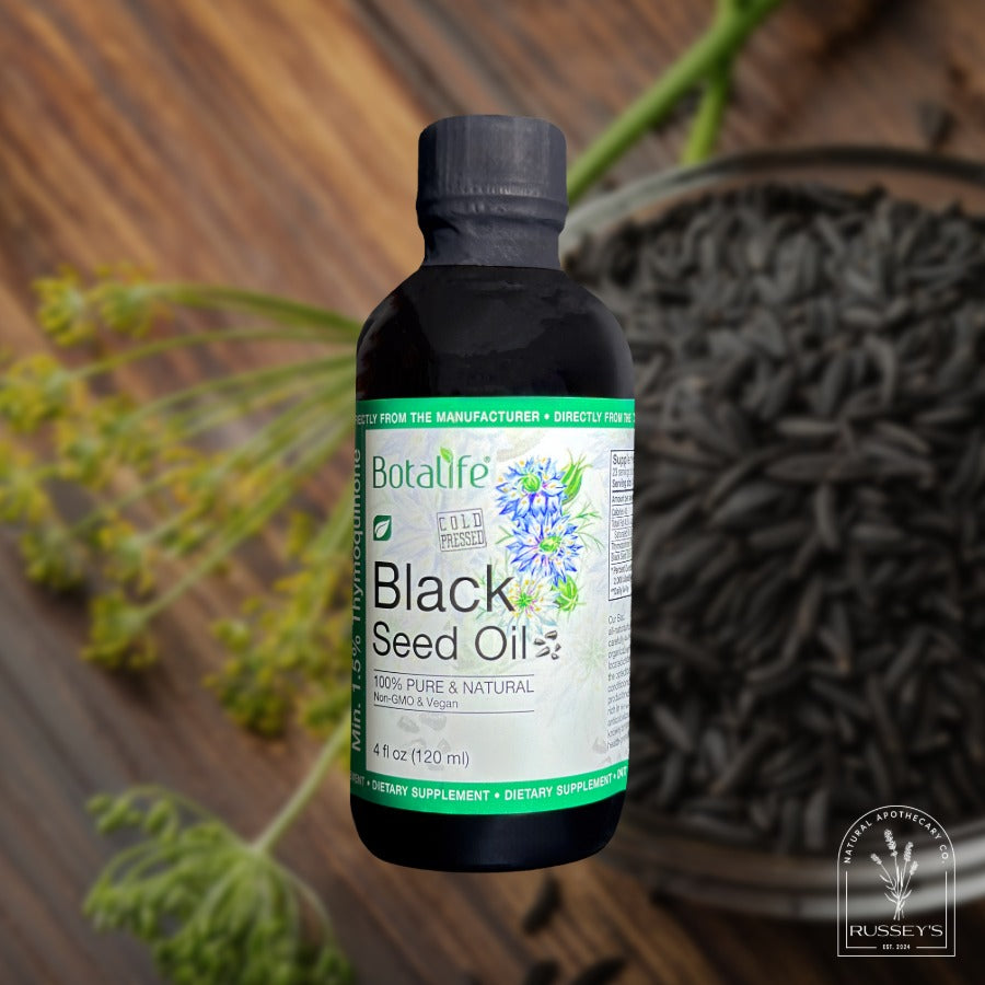 Bottle of Botalife Black Seed Oil with black seeds and plant leaves in the background